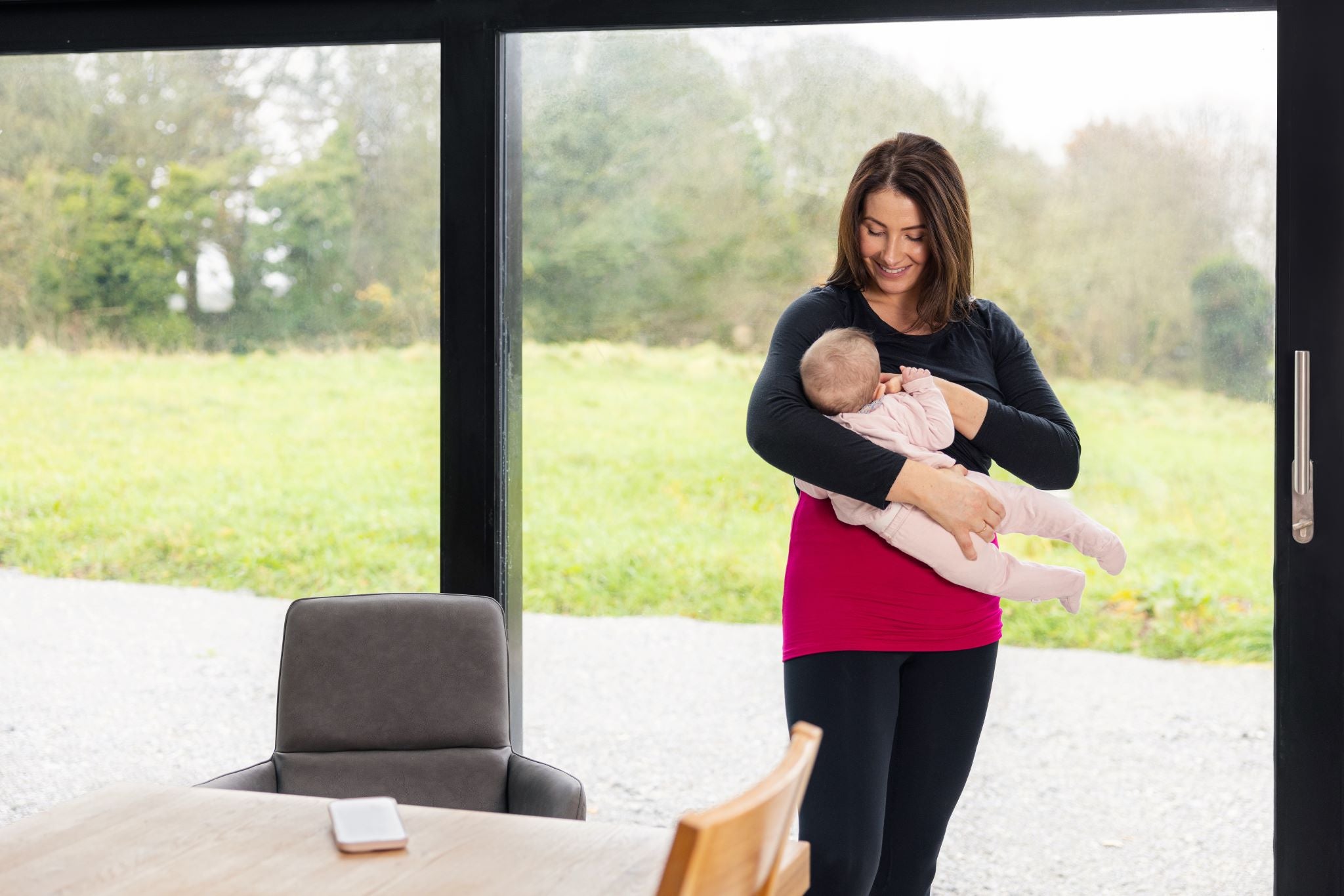 Breast Vest in Pink on mum breastfeeding baby whilst standing and smiling