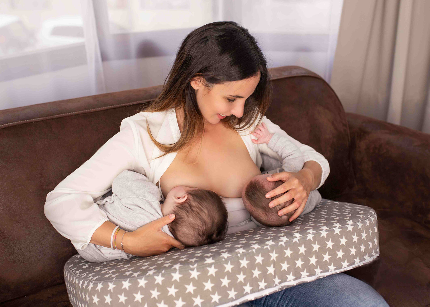 Mum breastfeeding twins with the use of a twin breastfeeding pillow